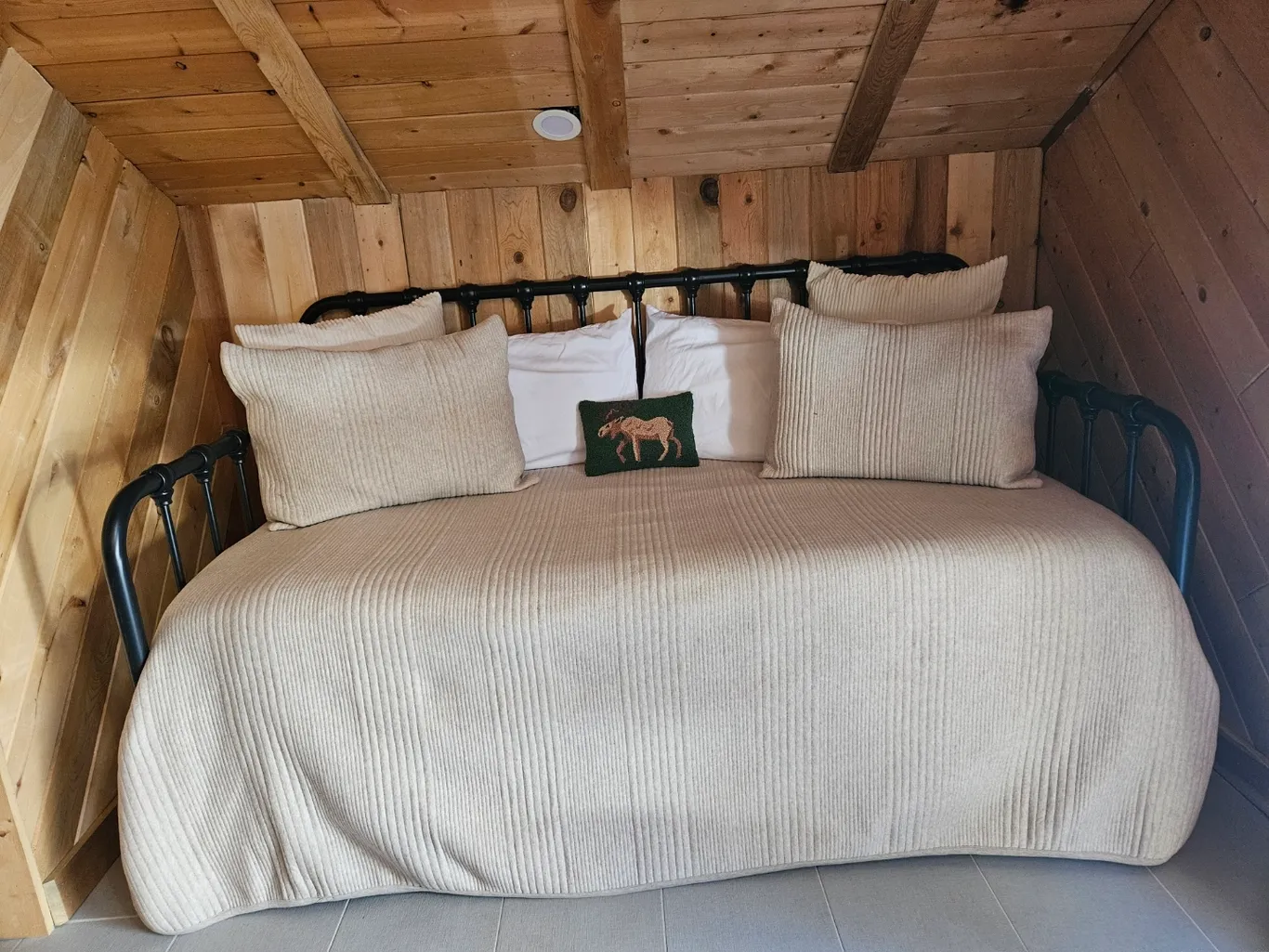 A cozy bed in a cabin with a wooden ceiling, highlighting the inviting atmosphere of the space. Cleaning services available.